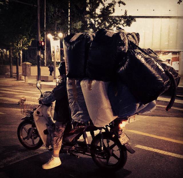 A local biking off with bags of clothing bought at one of the wholesale markets in Dongdaemun, Seoul, South Korea.